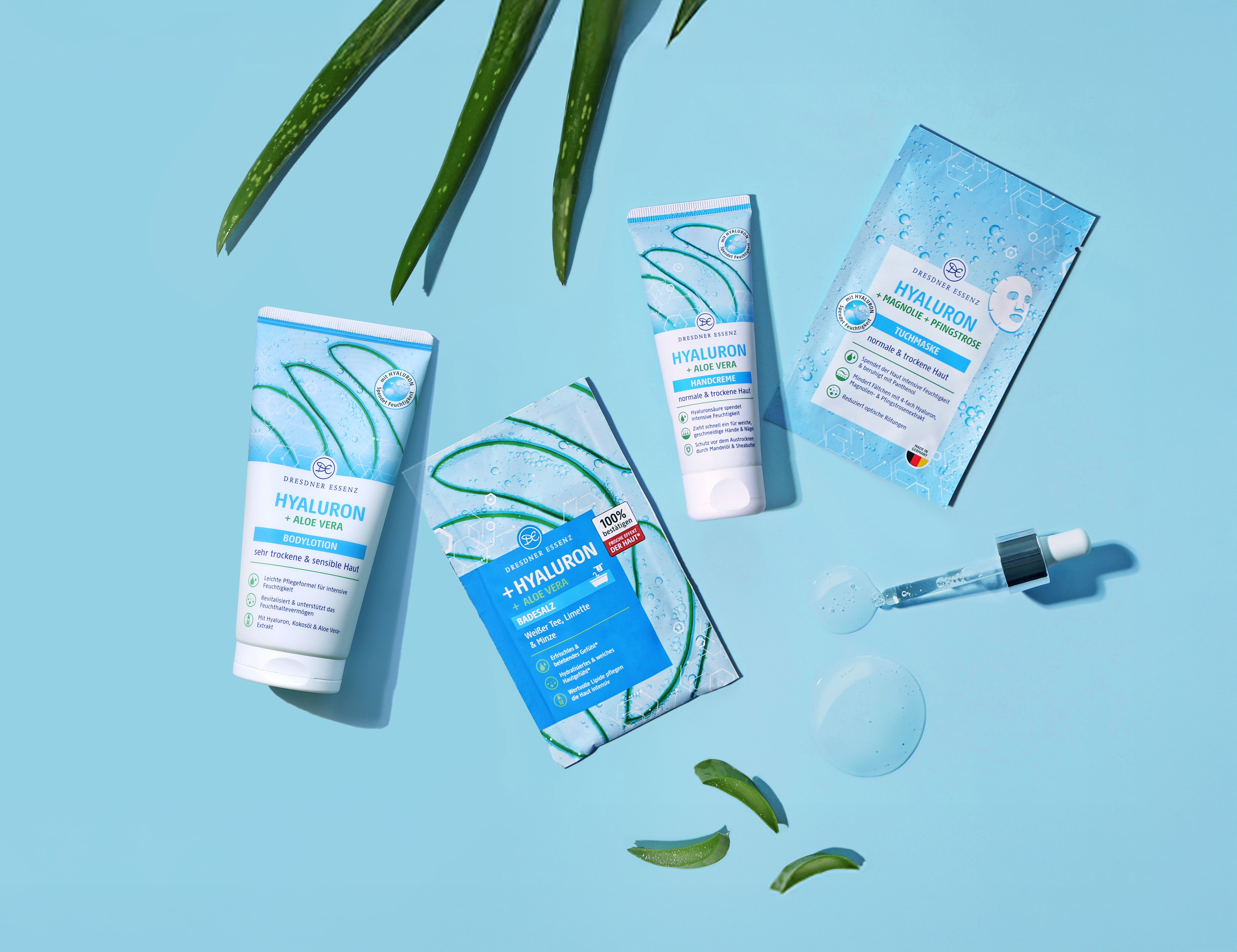 Die Produkte Badesalz, Tuchmaske, Handcreme und Bodylotion aus der Hyaluron Serie liegen nebeneinander und drum herum liegen dekorativ verschiedene Pflanzen und eine Pipette.