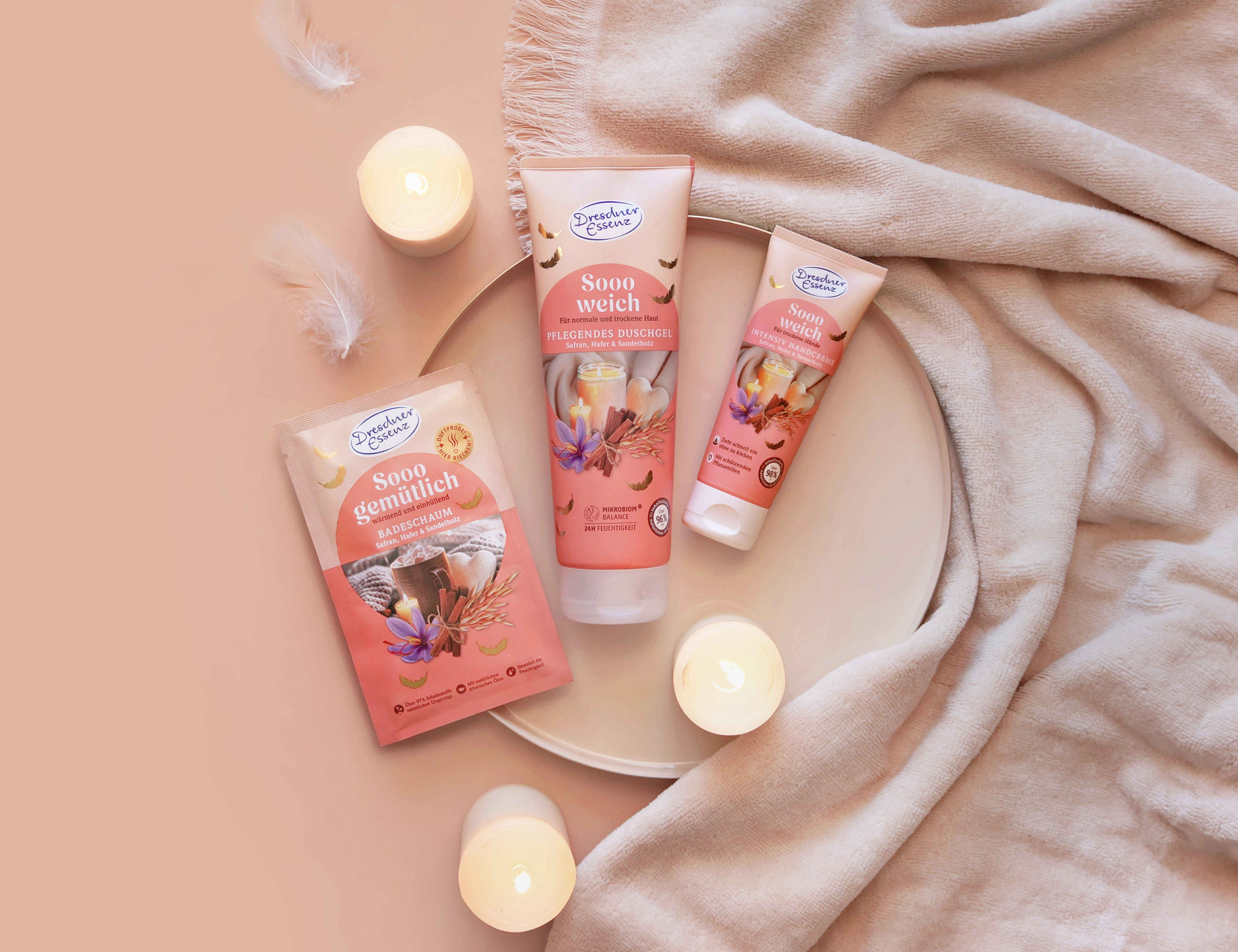 Produkte aus der Reihe Sooo weich / Sooo gemütlich Das Duschgel und die Handcreme "Sooo weich" sowie der Badeschaum "Sooo gemütlich" liegen in einer kuscheligen Umgebung mit Kerzen, Kuscheldecke und sanften Federn.