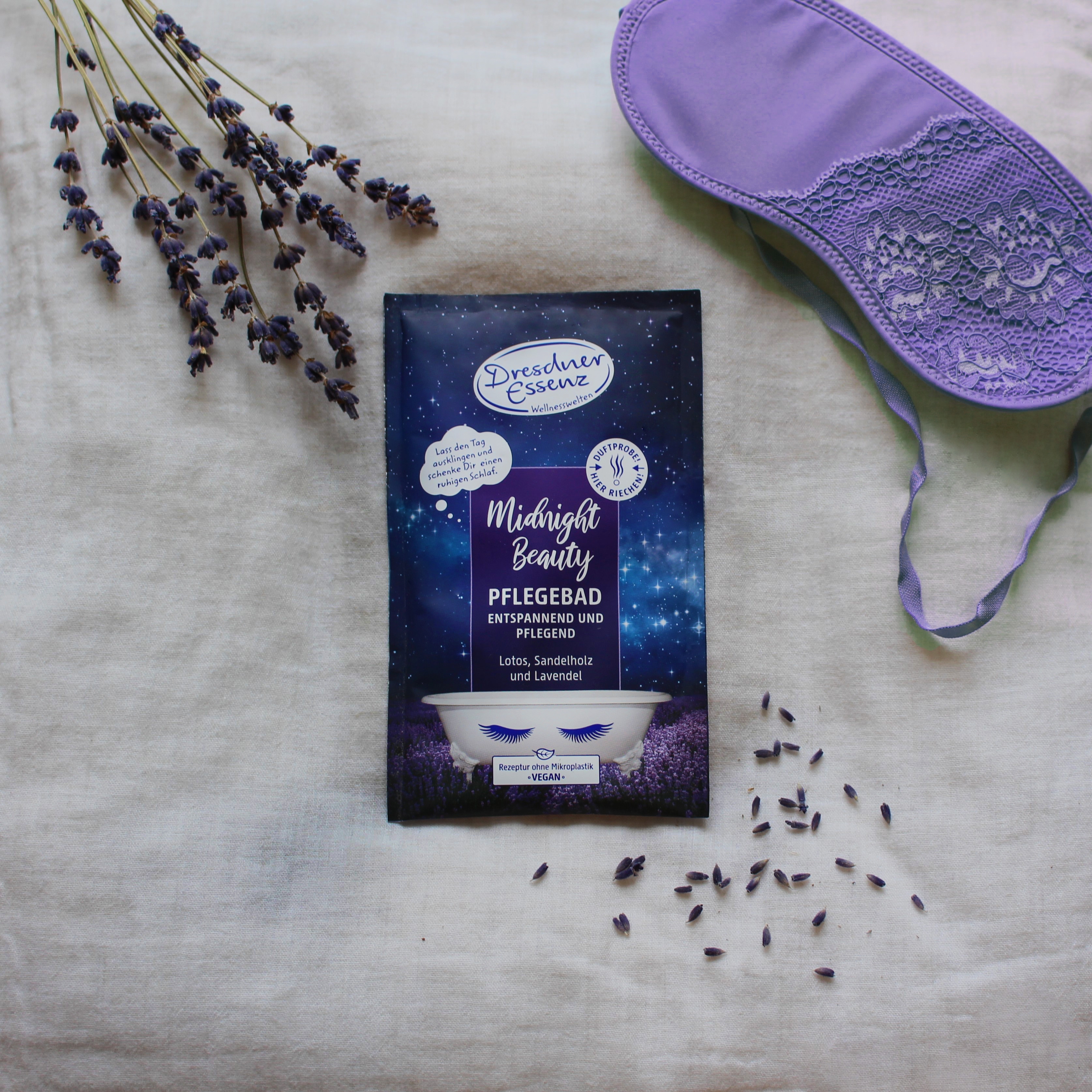 Pflegebad Midnight Beauty liegt auf einem weichen Untergrund neben Lavendel und einer Schlafmaske