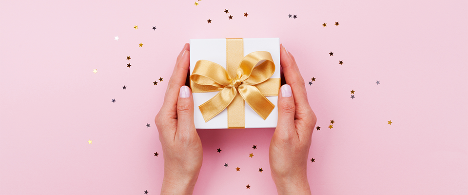 Abbildung eines verpackten Geschenkes mit goldenem Band und Glitzer