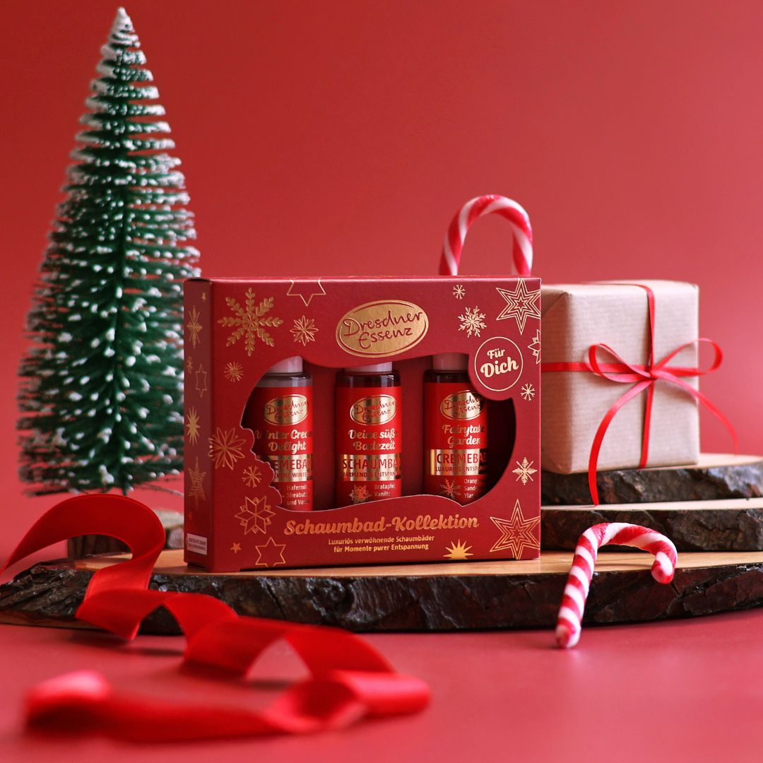 Das Geschenkset Schaumbad Kollektion steht vor einem kleinen Weihnachtsbaum und ist drum herum dekoriert mit rotem Band und Zuckerstangen.