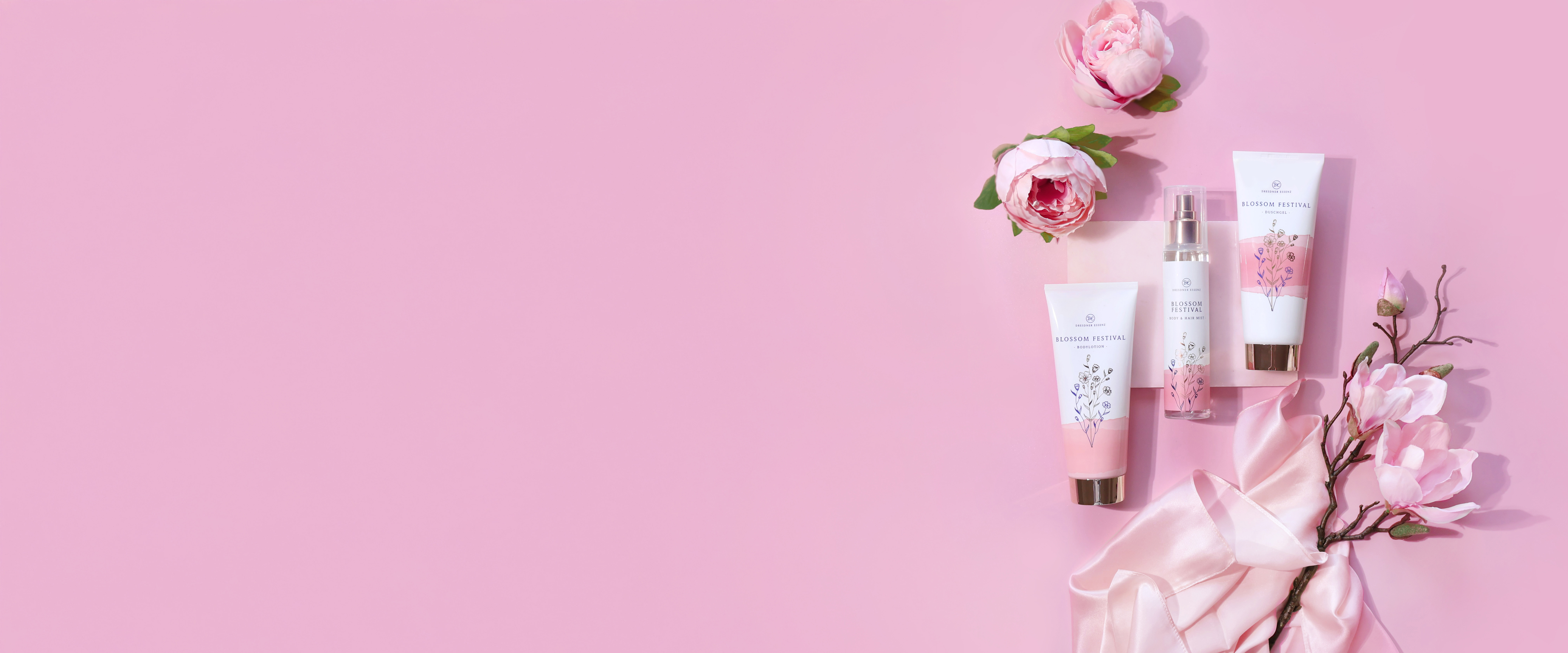 Die drei Produkte der Blossom Festival Serie liegen nebeneinander und sind drum herum dekoriert mit Rosen und weiteren Blueten und edlen Stoffen.