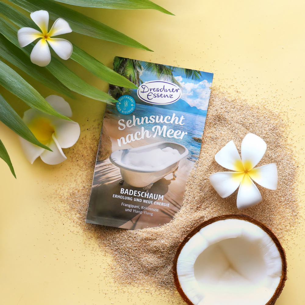 Das Badesalz ist mit Frangipani-Blueten, Sand und einer Kokosnuss dekoriert.