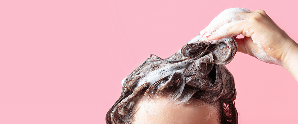 Abbildung eines Kopfes mit langen Haaren, der einshampooniert wird