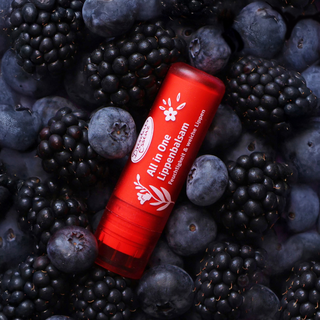 Der All in One Lippenbalsam liegt in einem Meer aus Blaubeeren und Brombeeren.