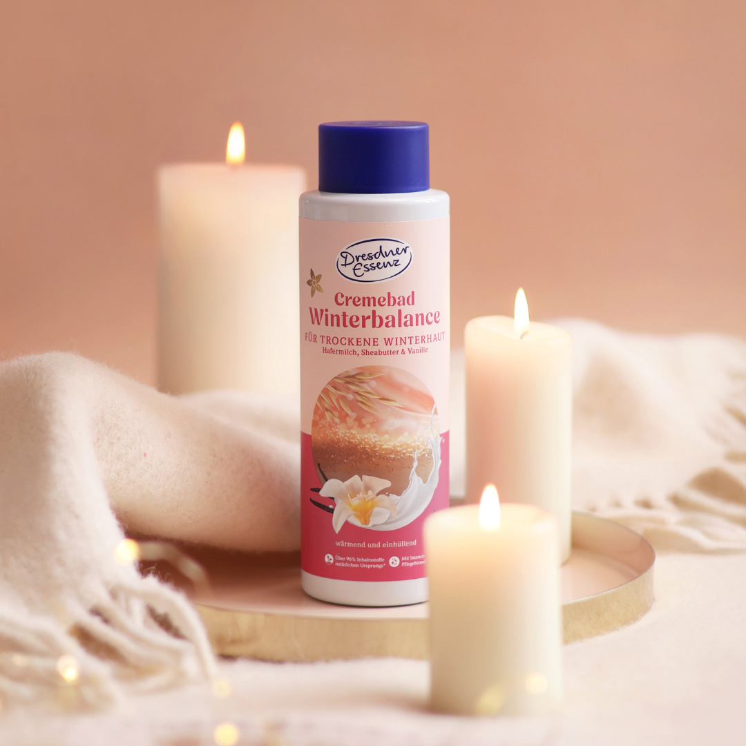 Das Cremebad Winterbalance steht in einer gemuetlichen Atmosphaere mit Kuscheldecke und leuchtenden Kerzen.