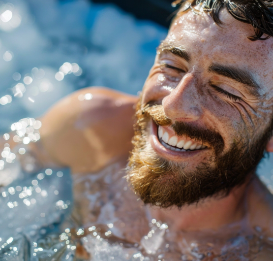 Ein laechelnder Mann liegt in einem Whirlpool und entspannt sich.