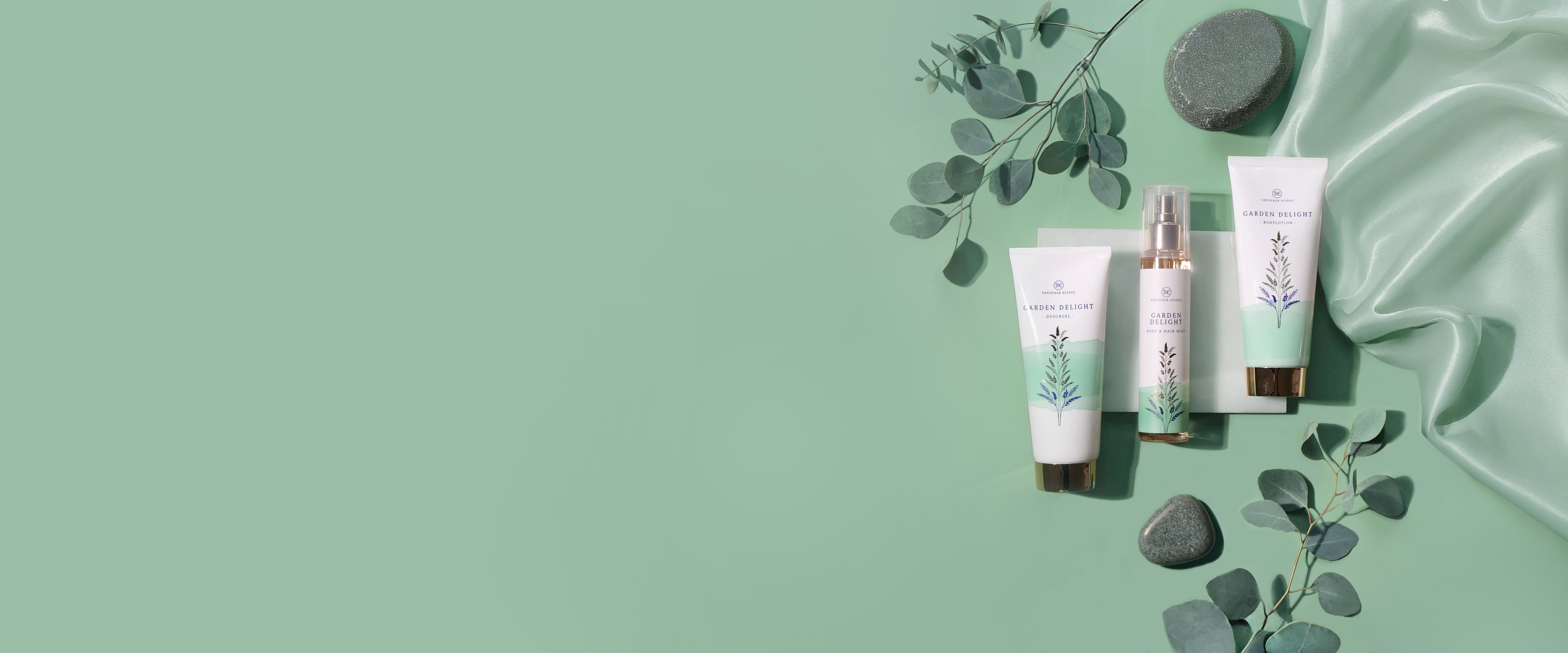 Die drei Produkte der Garden Delight Serie liegen nebeneinander und sind drum herum dekoriert mit Pflanzen, Blaettern und edlen Stoffen.