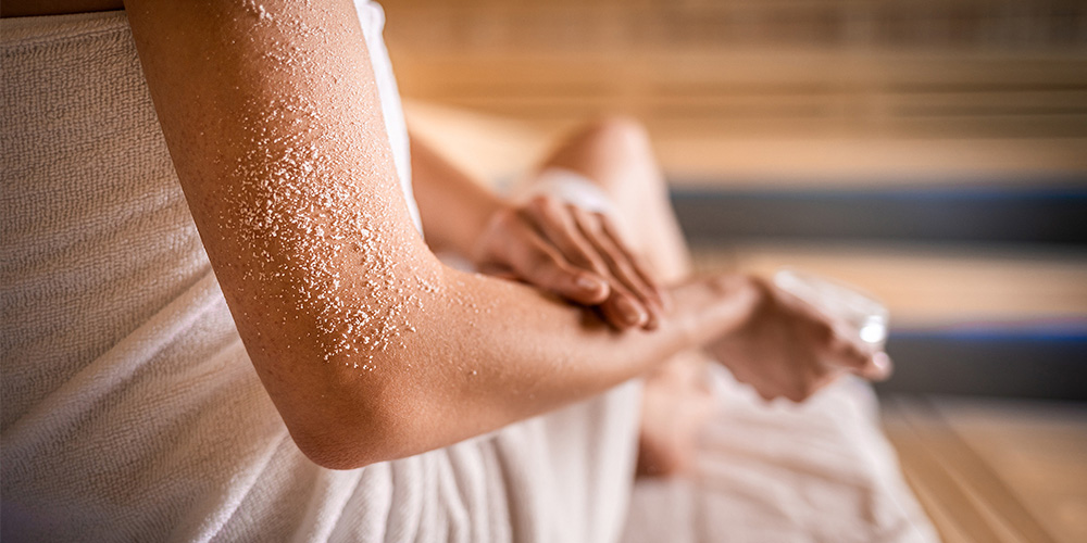 Nahaufnahme eines Armes, der in der Sauna mit einem Peeling eingerieben wird